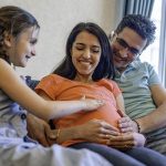 آموزش مسائل جنسی به کودکان ـ پدر، مادر و کودکی که با لمس شکم برآمده مادرش کنجکاوی خود را نشان می‌دهد