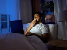 خمیازه مرد در تخت پشت لپتاپ